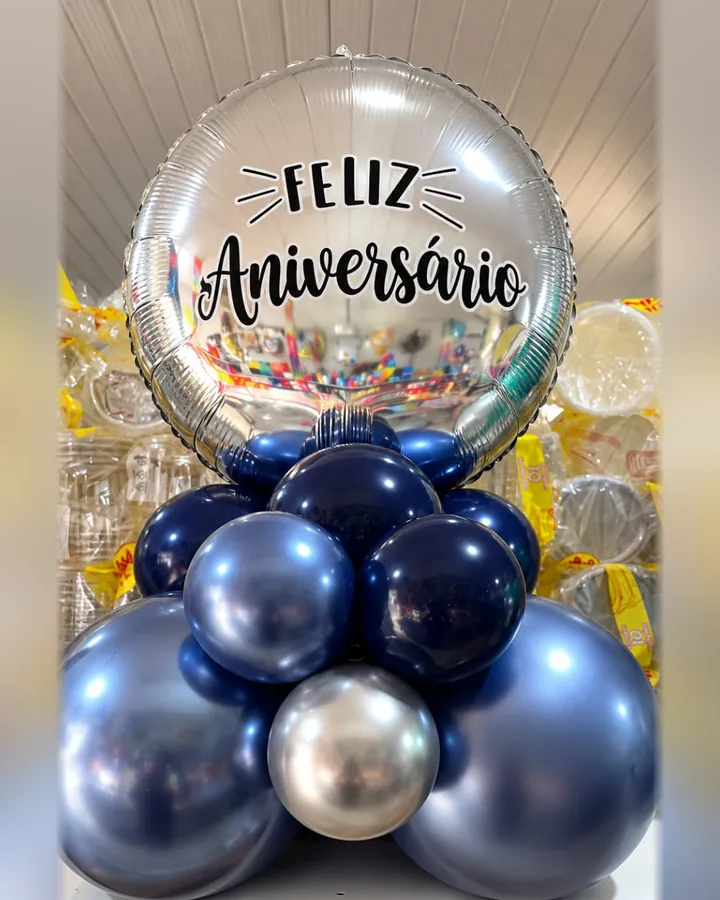 Balão prateado com a mensagem Feliz Aniversário e base de balões azuis e prateados.