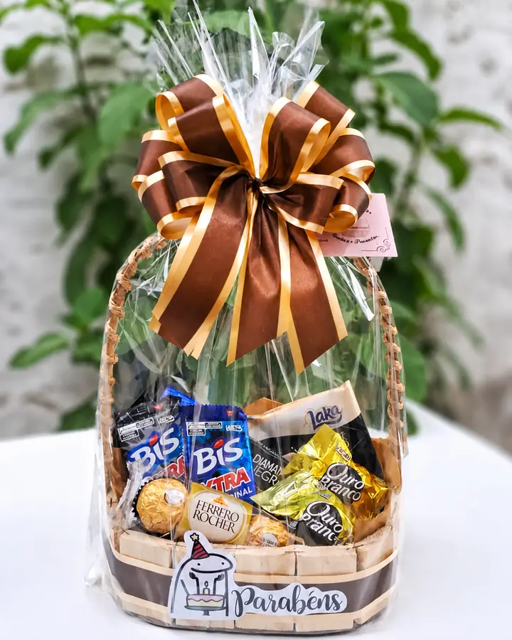Cesta de aniversário com chocolates, embalagem transparente e laço marrom e dourado