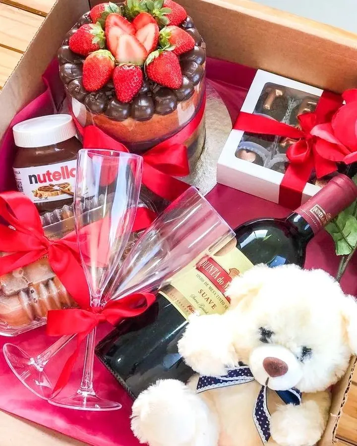 Cesta premium de aniversário com bolo de morango, vinho, taças, chocolates, rosas e ursinho