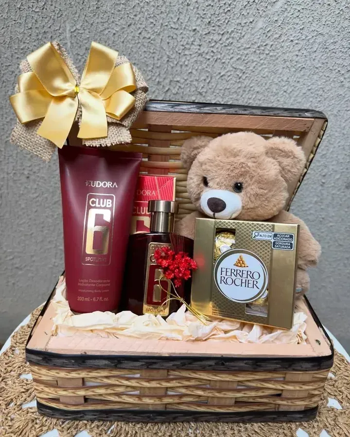 Baú de presente com laço dourado, ursinho, perfumaria e chocolates Ferrero Rocher.